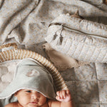 A baby wearing a hooded towel in quail design with wash bag nature trail beside