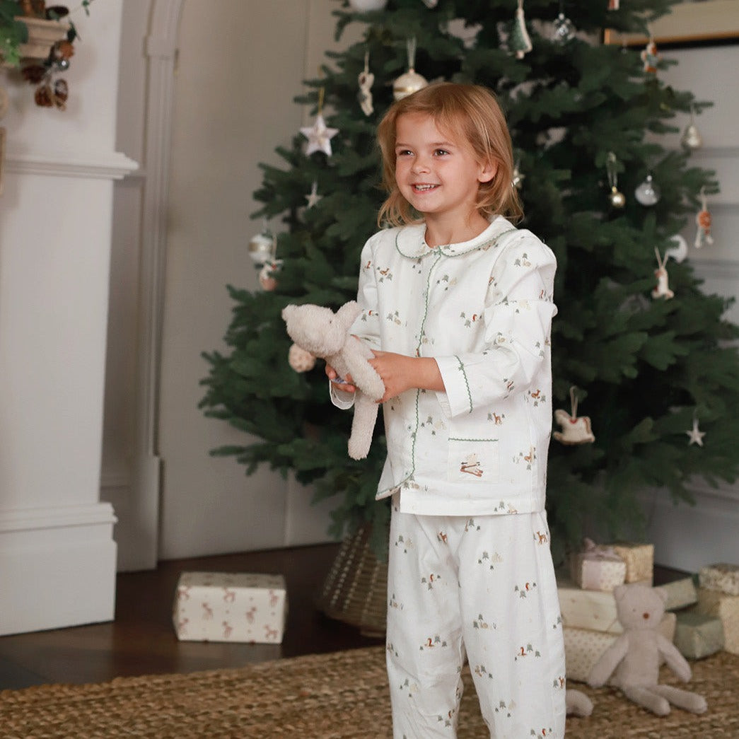 A girl wearing winter ski pyjamas while holding a teddy bear