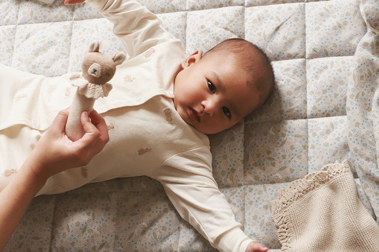 A baby playing while lying on a playmat nature trail