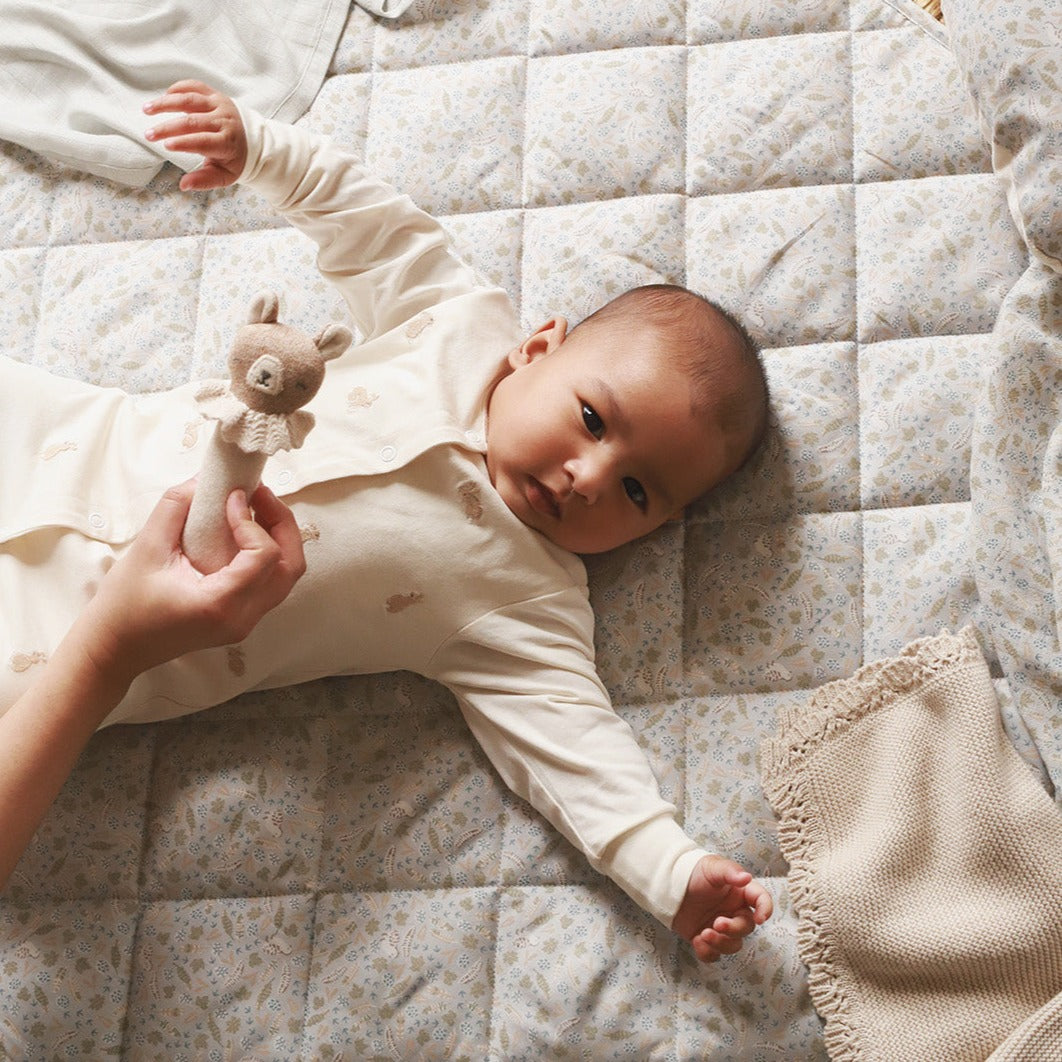 A baby playing while lying on a playmat nature trail