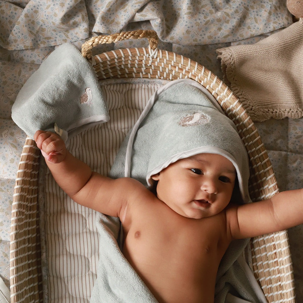 A baby wearing a hooded towel with bath mitt in quail design