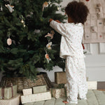 A boy wearing a nutcracker pyjamas while decorating the Christmas tree