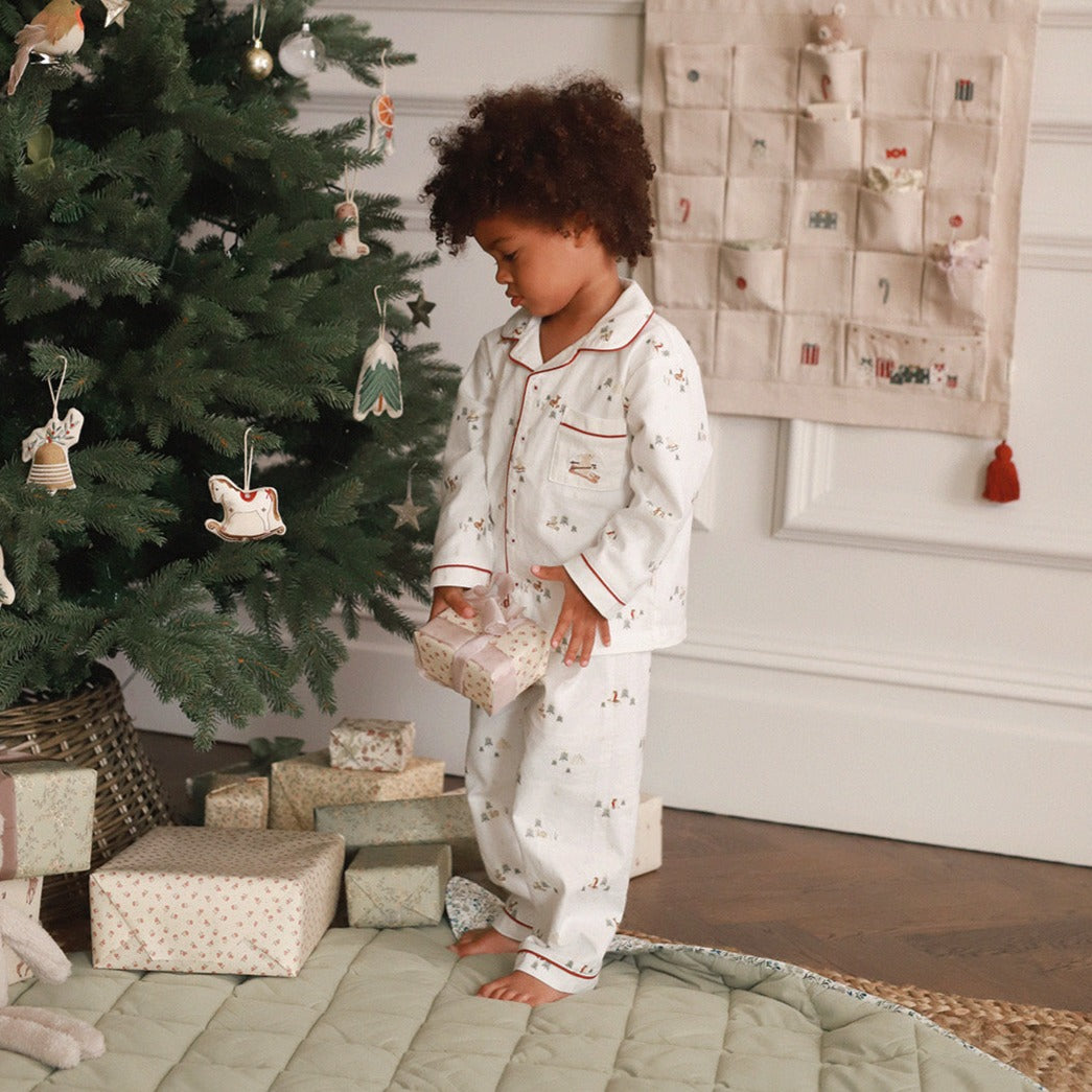 A boy wearing a nutcracker pyjamas while holding a gift