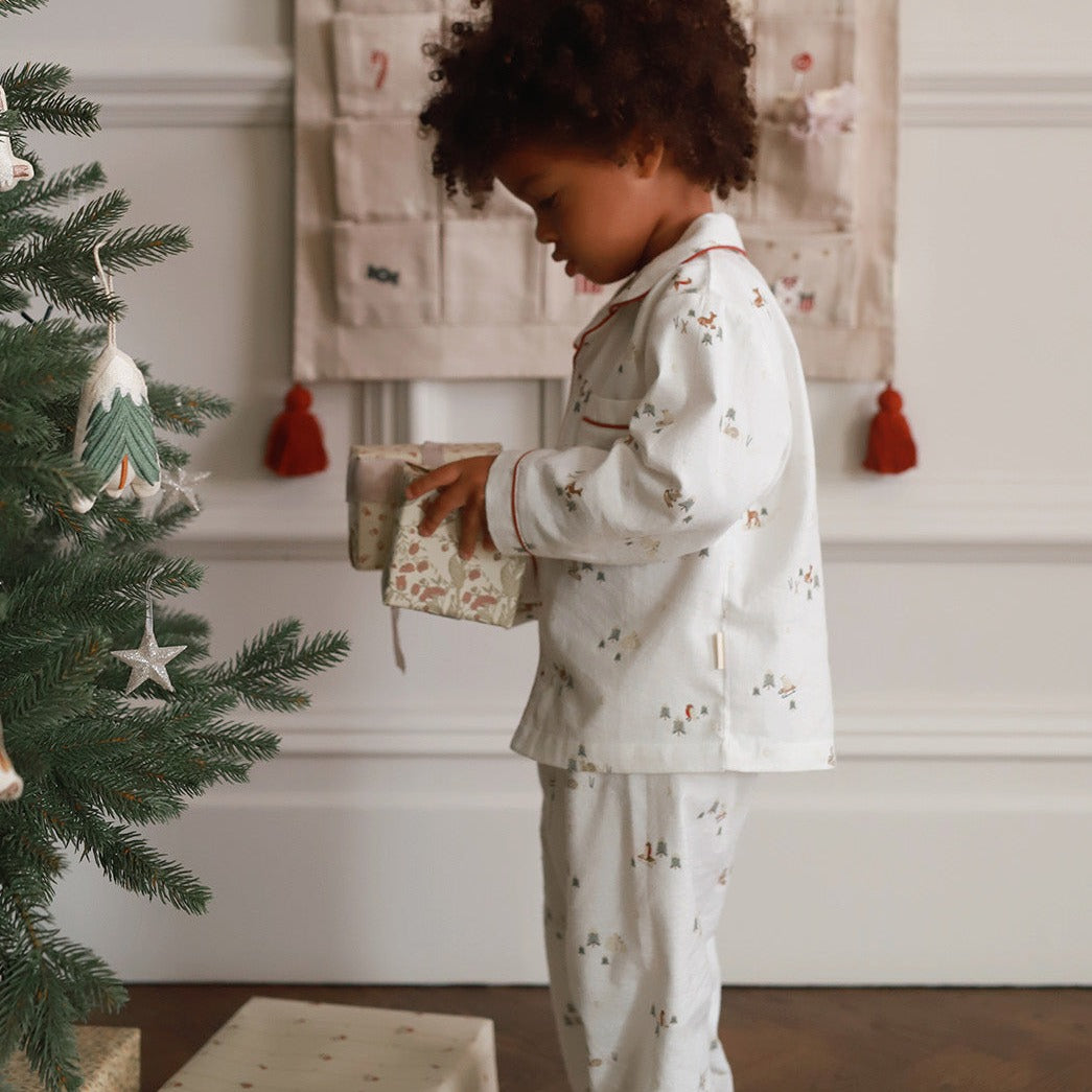 A boy wearing a nutcracker pyjamas while unboxing a present