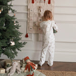 A girl on pyjamas standing next to Christmas advent calendar