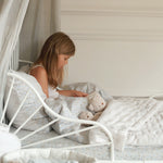 A girl reading while seated on a nature trail bedding set with quilted bedspread in natural stripe