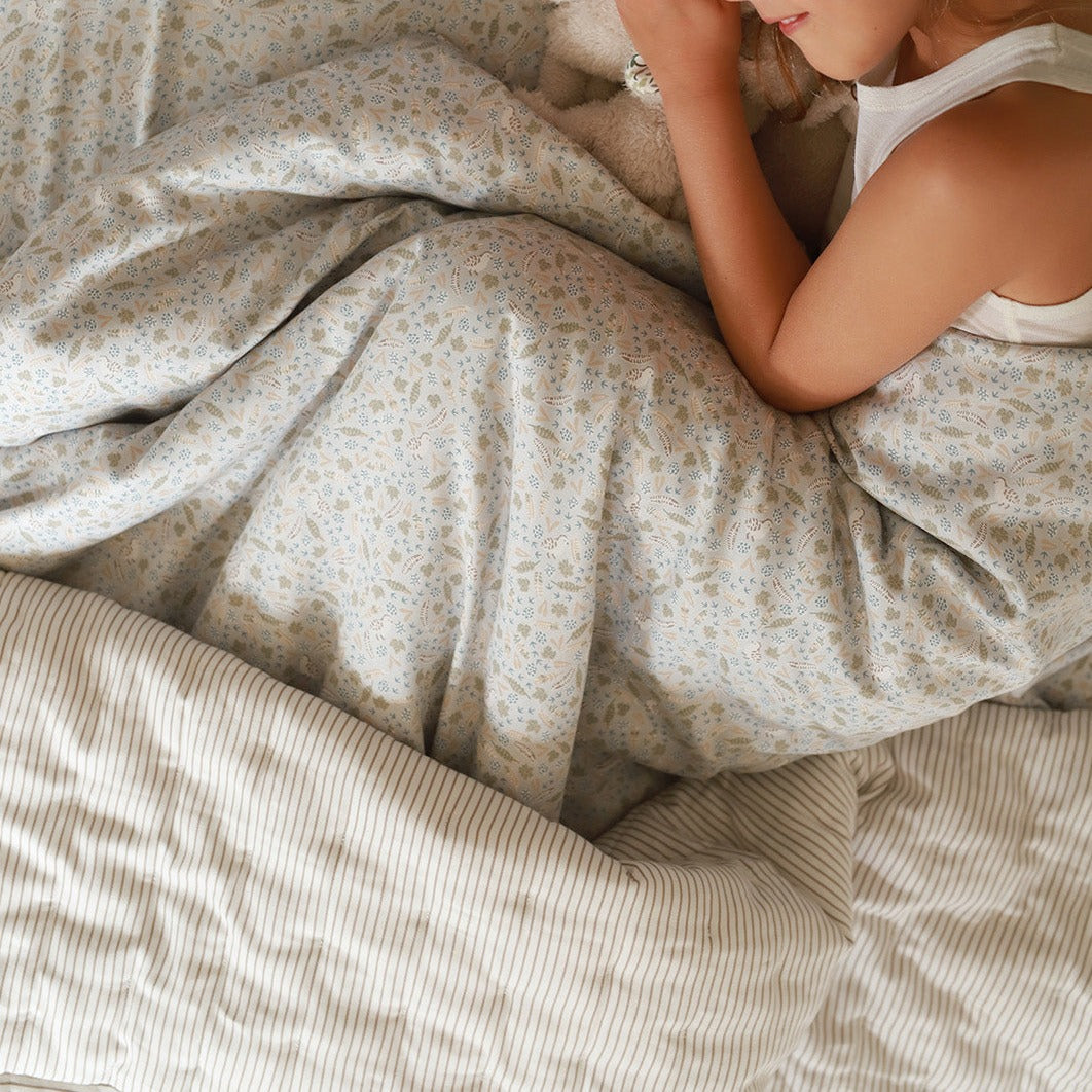 A girl snuggling a nature trail duvet with quilted bedspread natural stripe