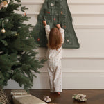 A girl wearing a nutcracker pyjamas reaching the advent calendar