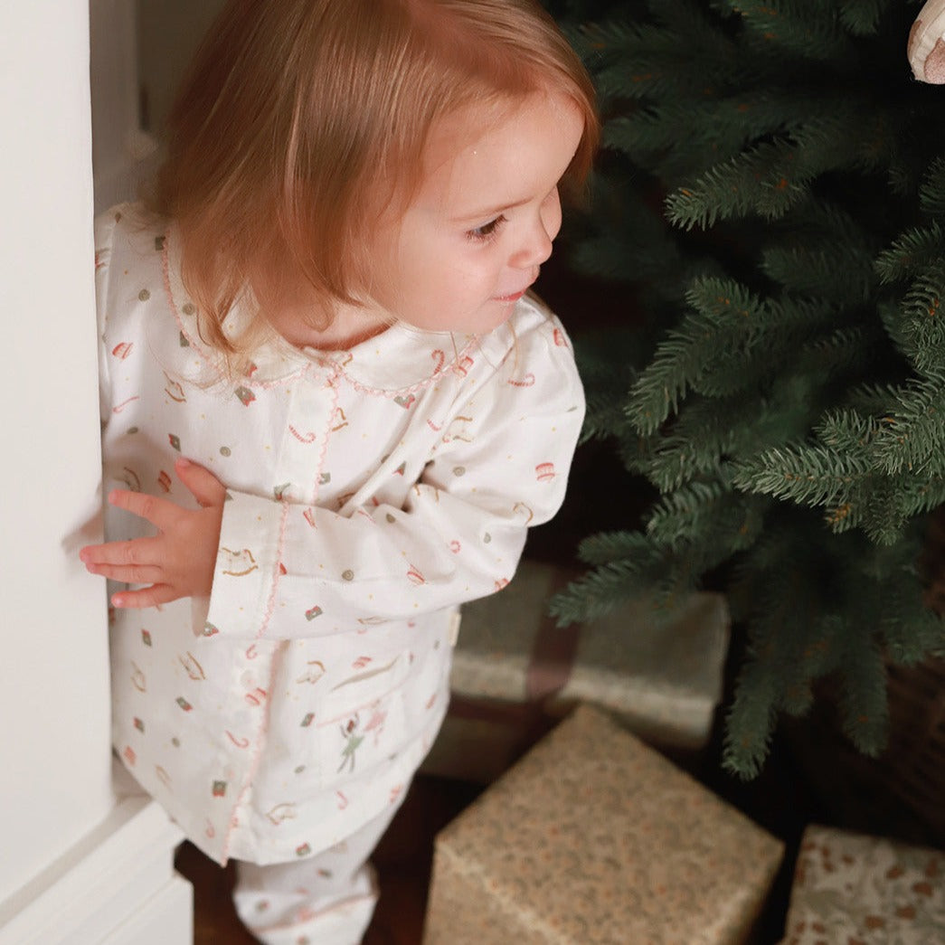 A girl wearing a nutcracker pyjamas standing near the Christmas tree with presents