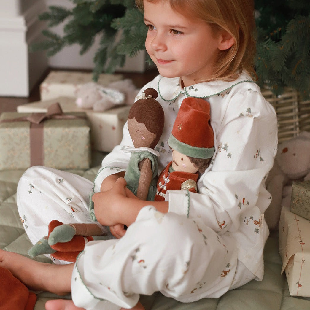 A girl wearing pyjamas in winter ski design holding nutcracker dolls