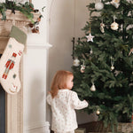 A little girl standing next to the chimney with nutcracker Christmas stocking