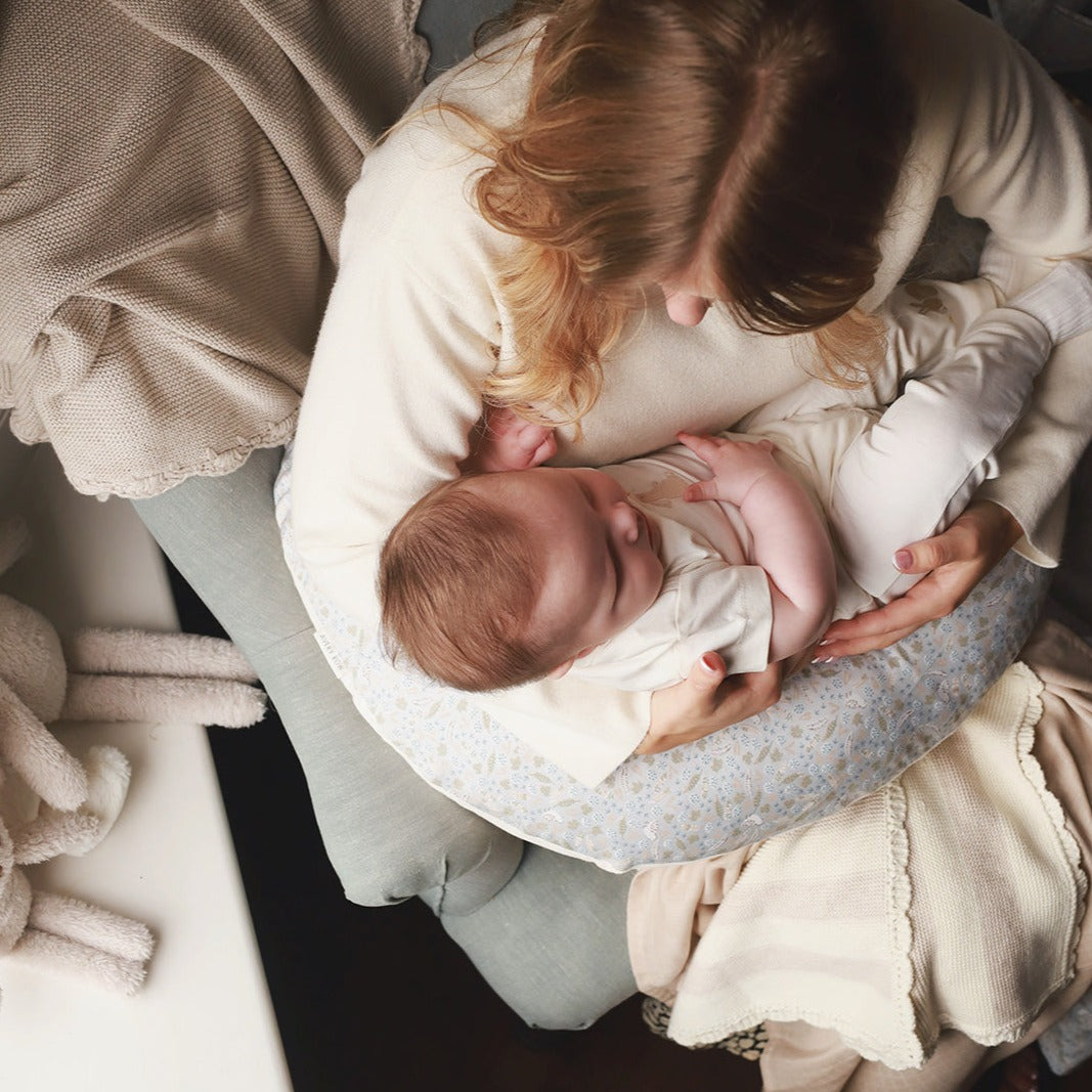 A mom snuggling her baby with a nursing pillow nature trail