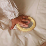 A tiny hand placed playing with the mirror on top of activity mat chamomile