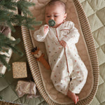 Baby in nutcracker sleepsuit with pacifier and deer rattle toy