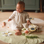 A baby playing on activity mat chamomile with fabric book
