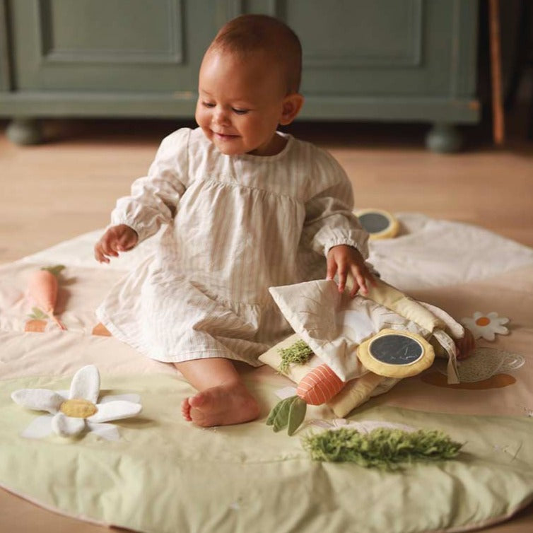 A baby playing on activity mat chamomile with fabric book
