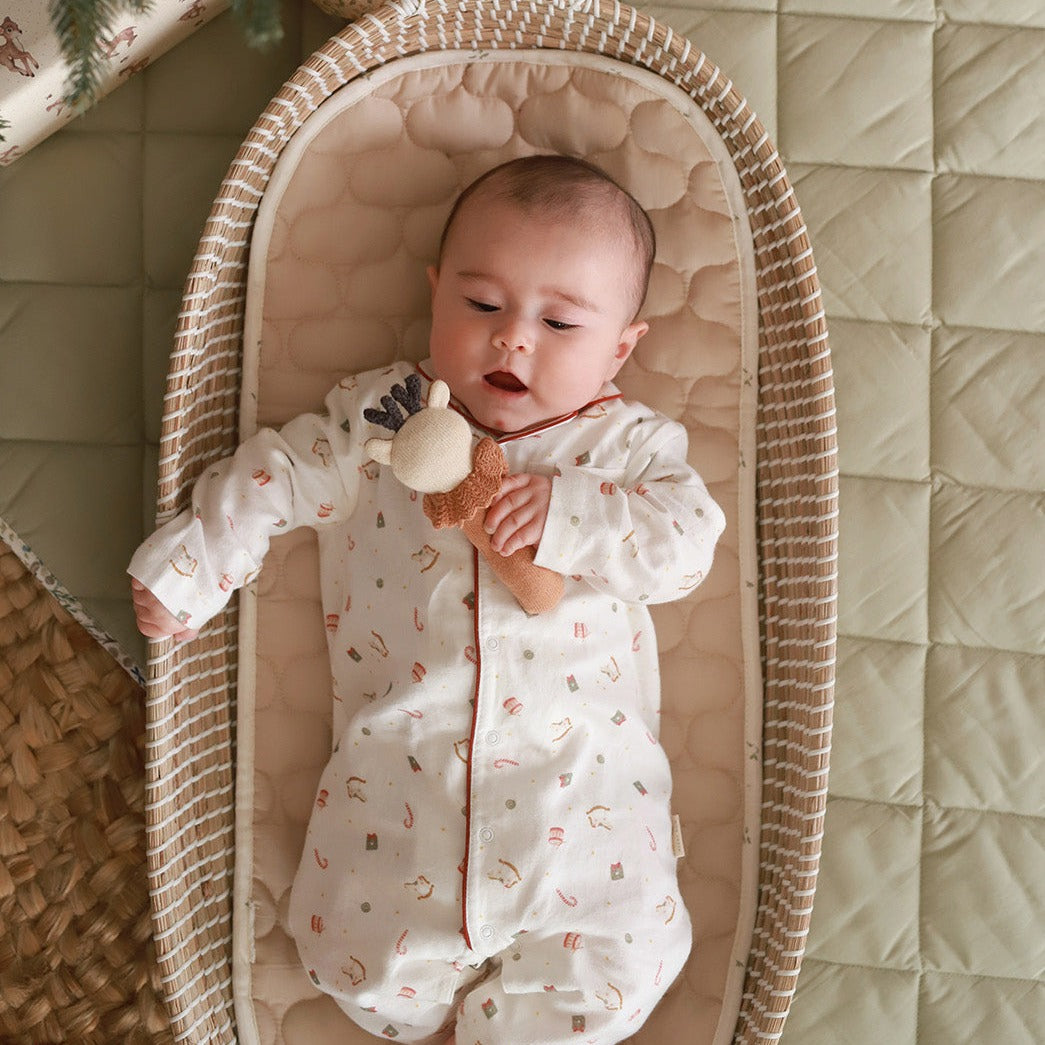 A baby wearing sleepsuit in nutcracker design holding a rattle toy