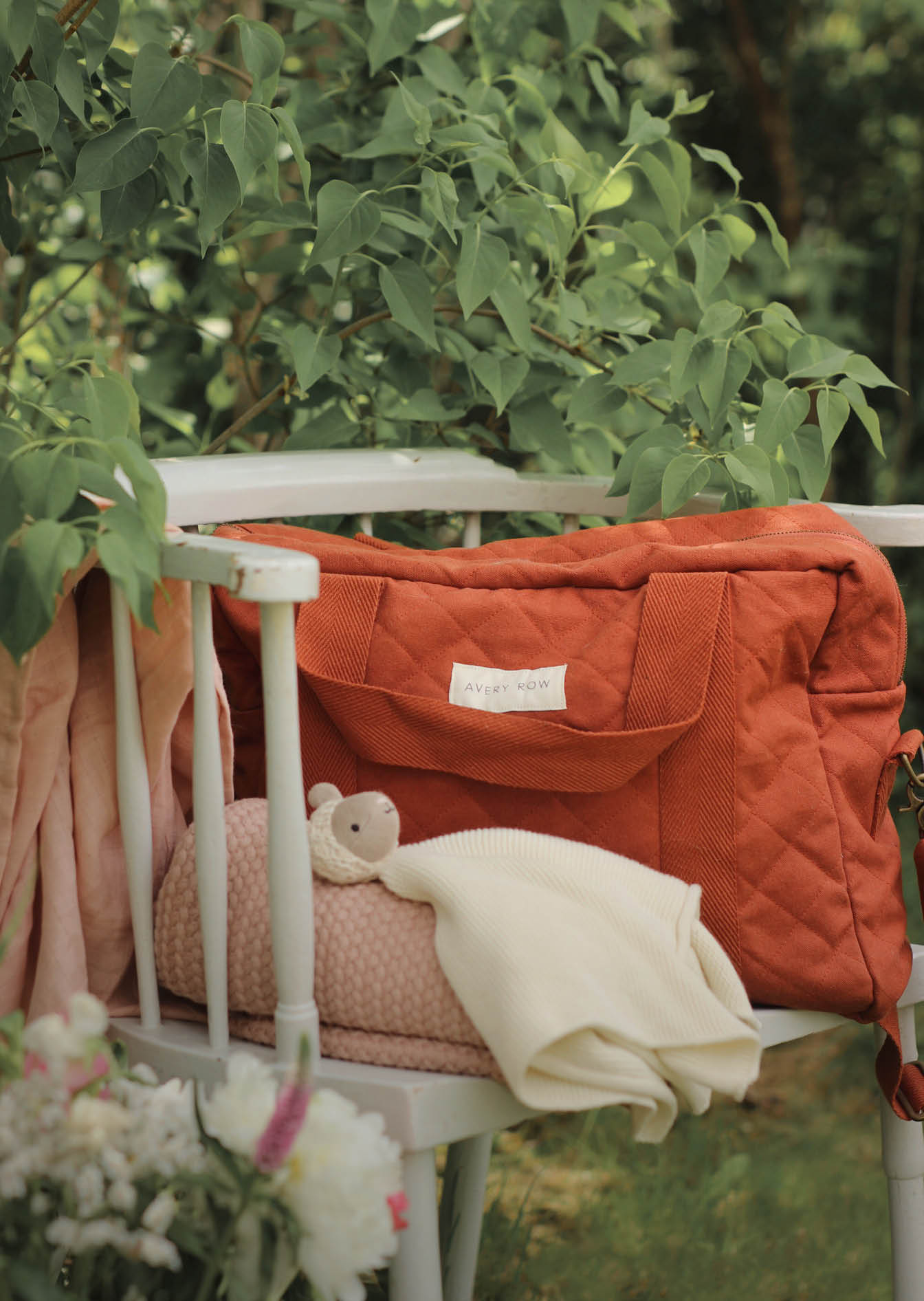 Cinnamon Changing Bag with Changing Mat and Muslins. Presented on a chair in the warm spring air.
