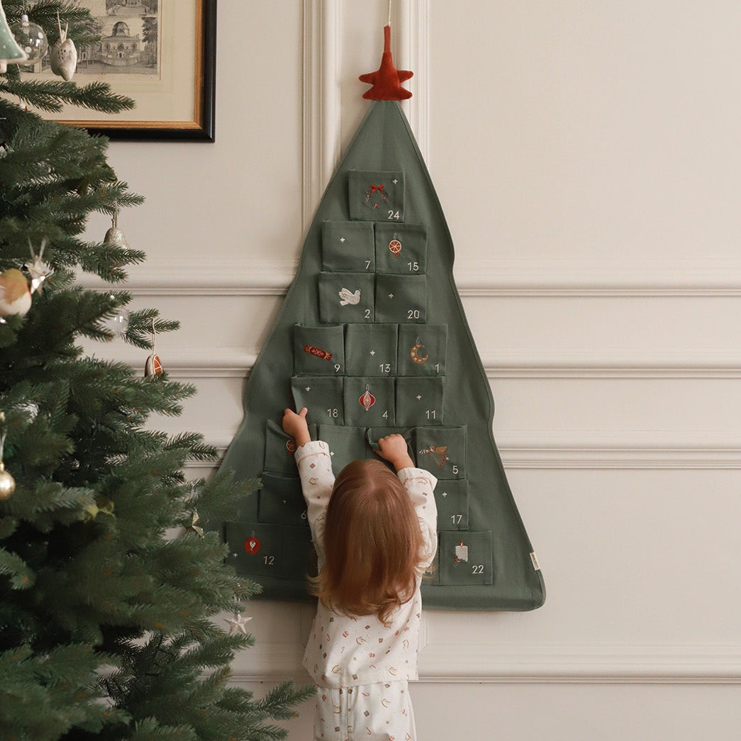 Kid playing with Christmas Tree Advent Calendar on the Wall