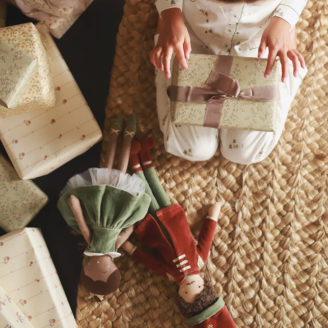 Nutcracker dolls lying next to a kid unboxing a present