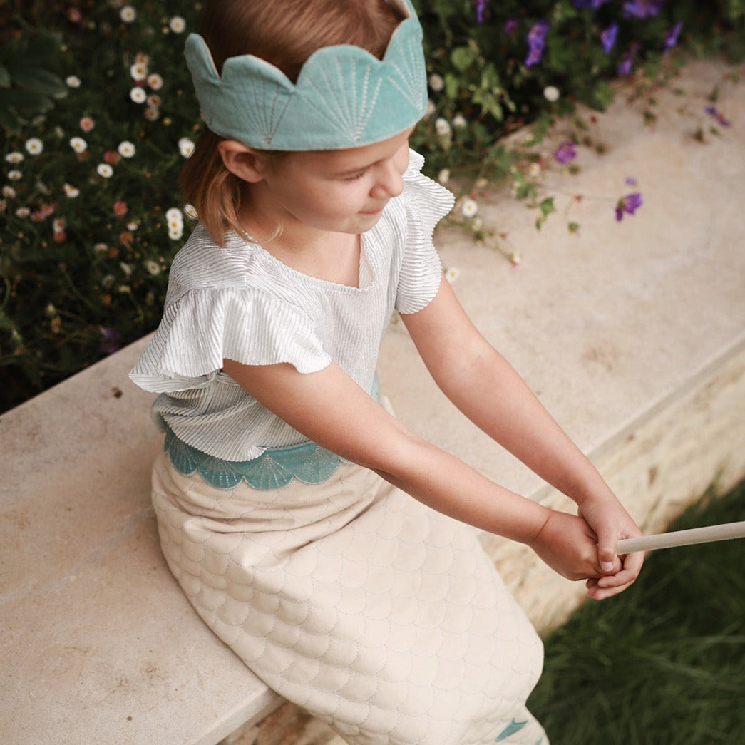 sea-blue velvet crown worn by a girl sitting on a wall