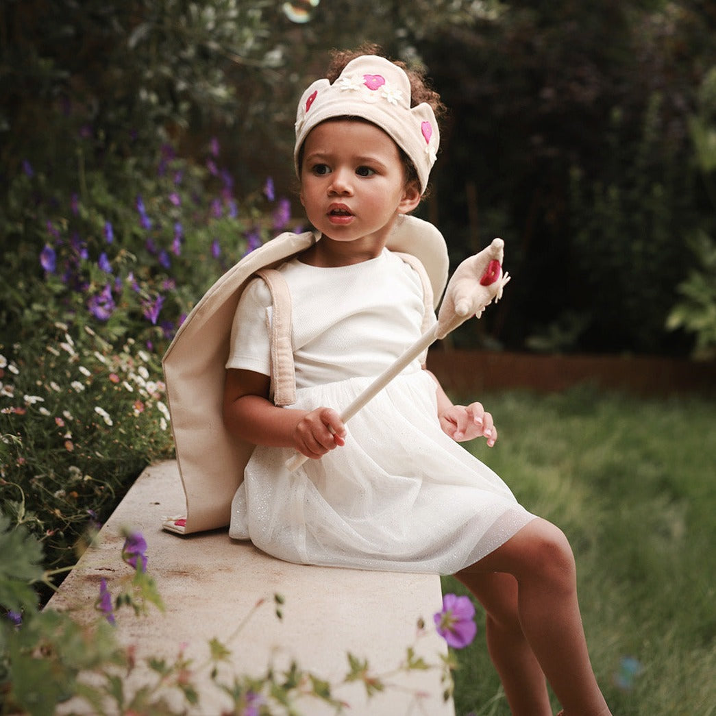 velvet flower fairy dress up with canvas wing and star wand worn by a girl sitting in a garden