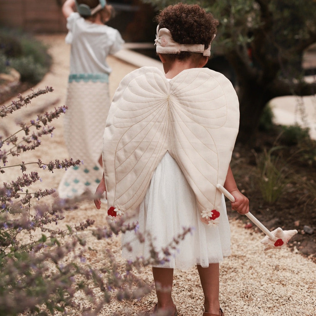 canvas wings and velvet flower fairy dress up worn by a girl walking with her playmate