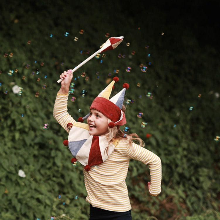 red, blue and yellow cotton jester 3-piece set worn by a kid playing with bubbles