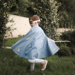 a boy wearing a blue cotton percale cape twirling